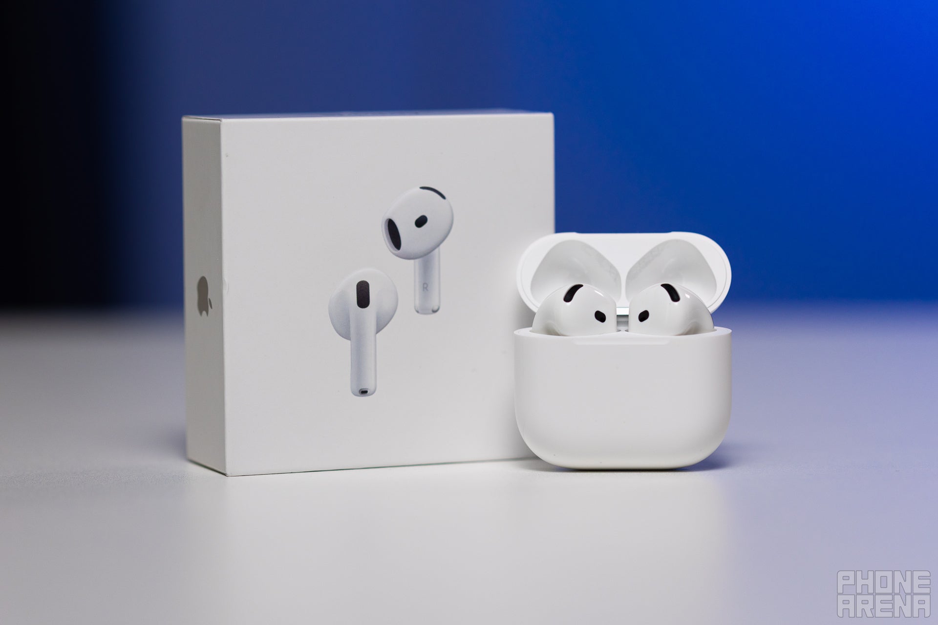 AirPods 4 in their case, with the lid open, standing next to the shipping box