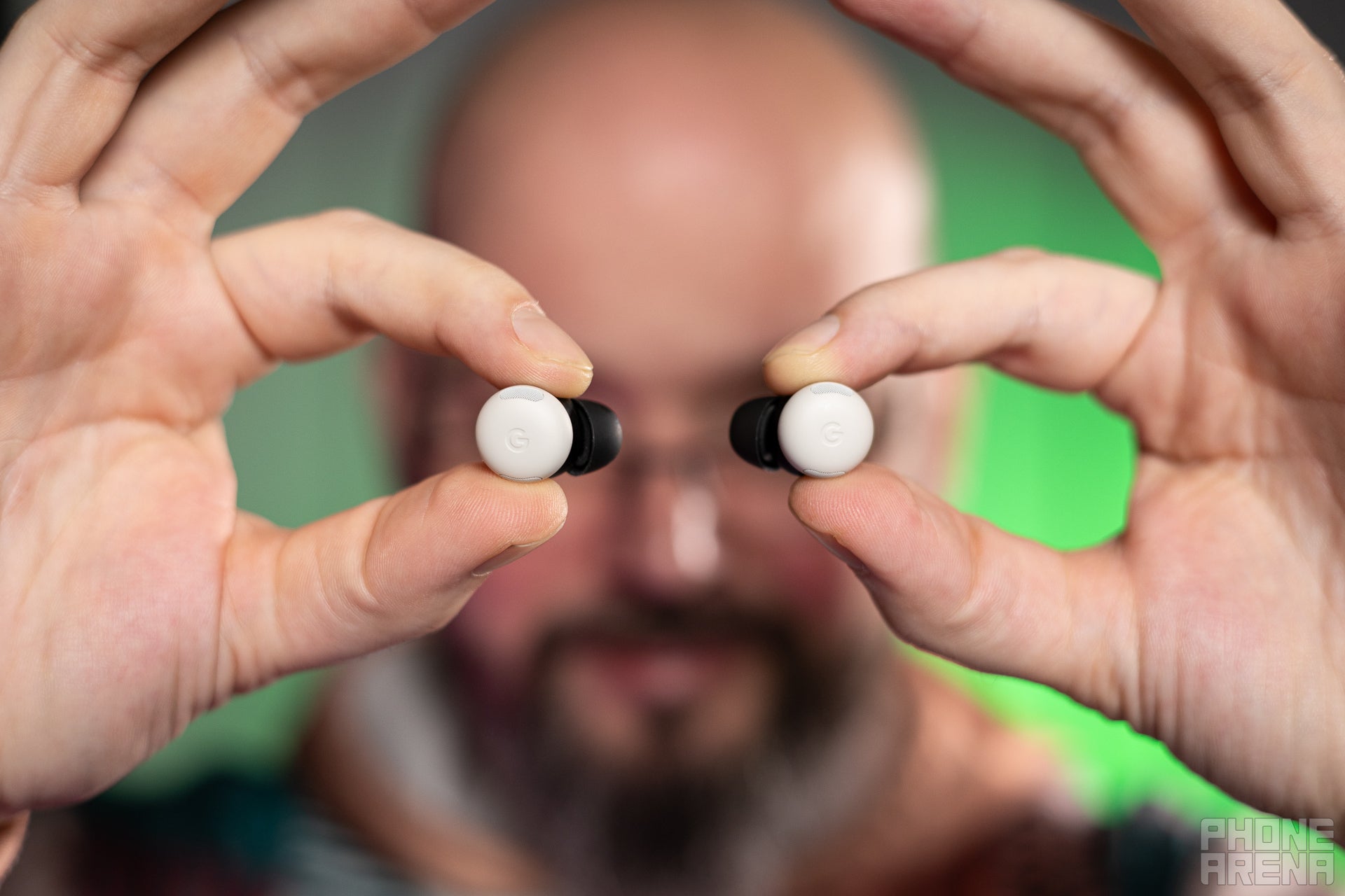 Presenter holding Google Pixel Buds Pro 2 up, the photo is framed so it looks like the Buds are in place of his eyes