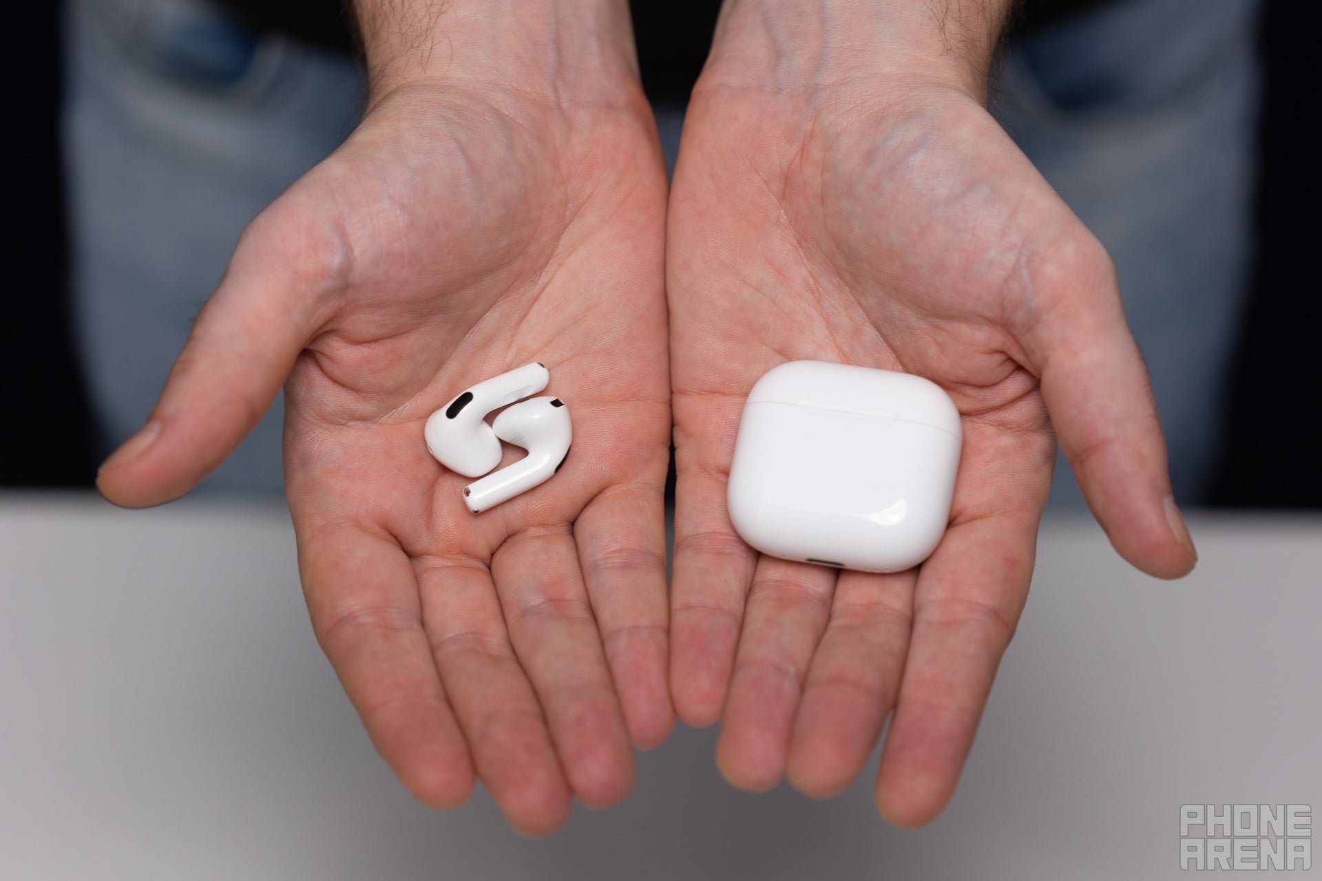 AirPods and their case, held in hands, showing off how tiny they are.